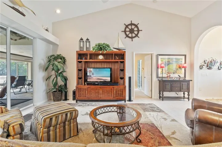 Living room with arched walkways, tile patterned floors, and high vaulted ceiling