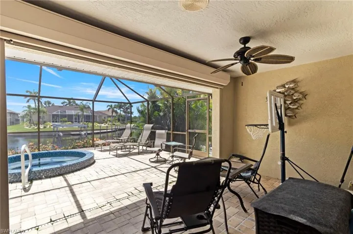 View of patio / terrace featuring an in-ground hot tub, a water view, a residential view, a ceiling fan, and glass enclosure