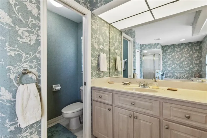 Bathroom with wallpapered walls and vanity