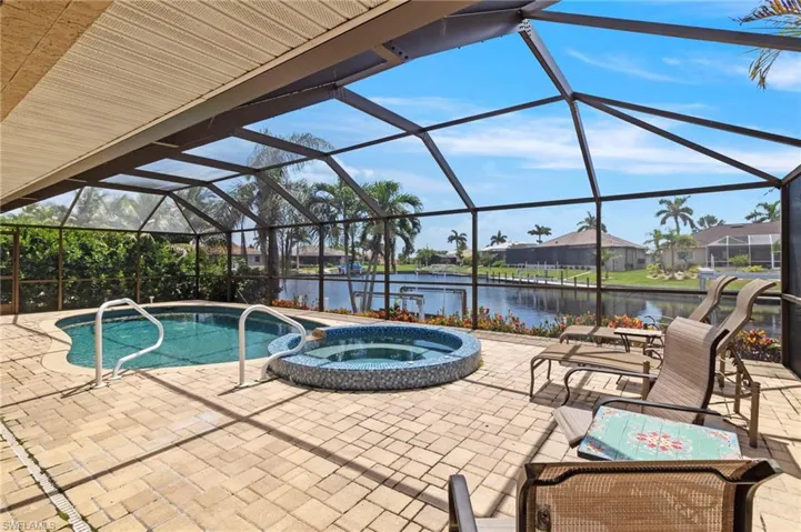 View of swimming pool featuring a patio, a pool with connected hot tub, a water view, and a lanai