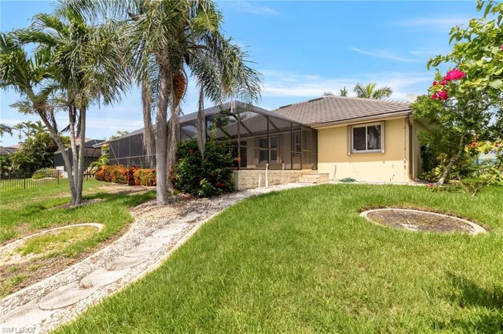 Rear view of house featuring a yard, a tile roof, stucco siding, and a lanai