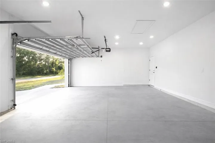 Spacious garage featuring a concrete floor, white walls, and recessed lighting