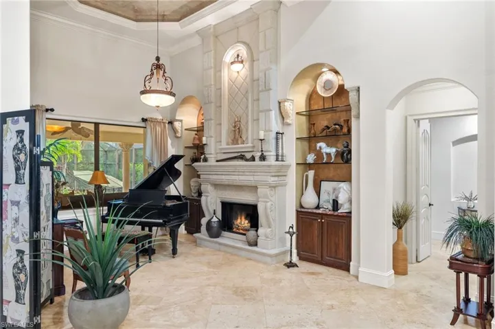 Living room with built in shelves, marble floors, a fireplace, and a high ceiling.