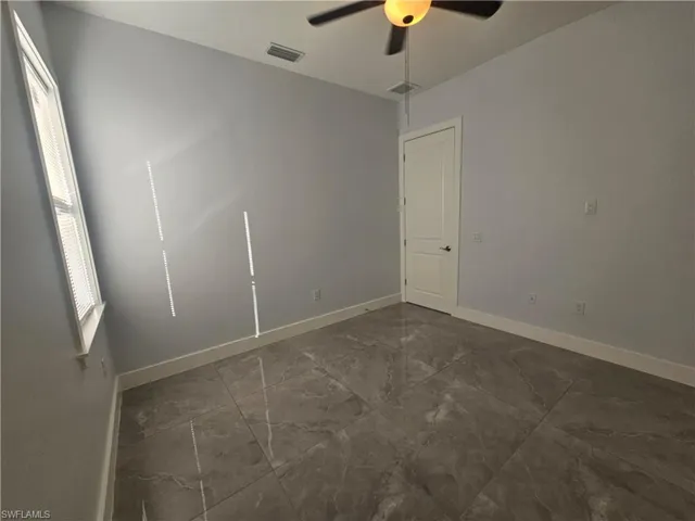 Empty room featuring ceiling fan and dark marble finish floors