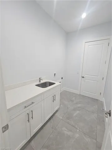 Laundry room with hookup for a washing machine, cabinet space, and light marble finish flooring