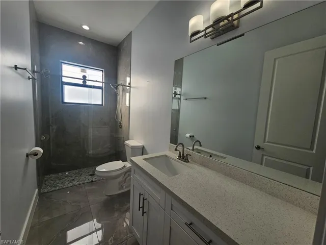 Full bathroom with a shower stall, vanity, and dark marble finish floors