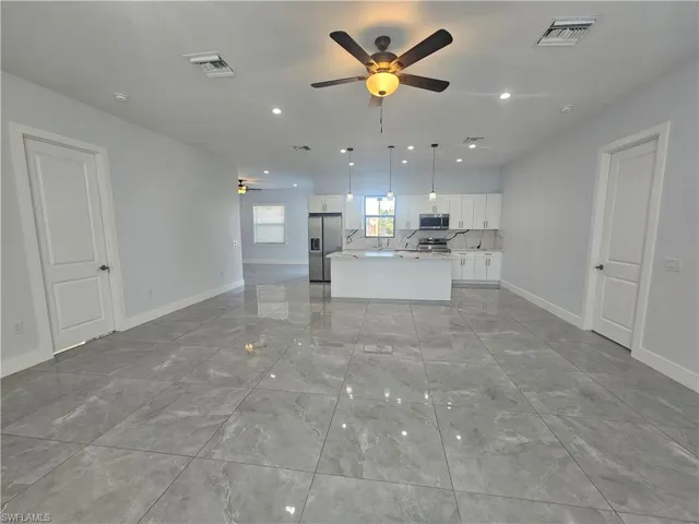 Unfurnished living room with a ceiling fan, recessed lighting, and light marble finish flooring