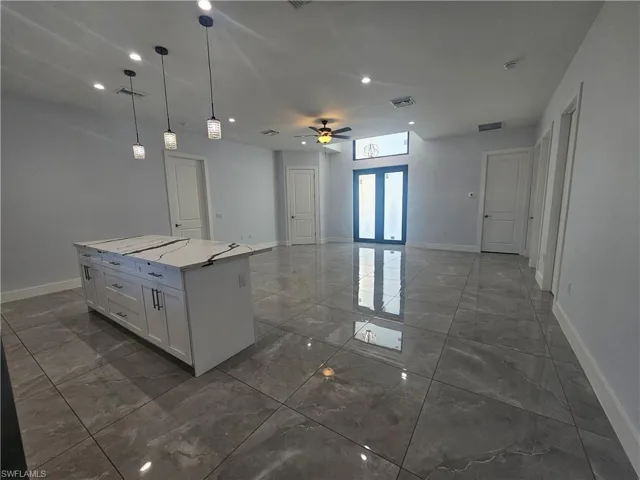 Kitchen featuring hanging light fixtures, a ceiling fan, open floor plan, french doors, and light marble finish floors