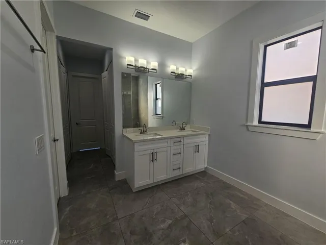 Full bathroom with double vanity and baseboards