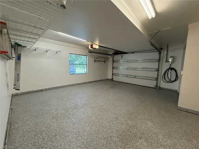 Garage with built in metal wall shelving units and a Tesla / EV charger