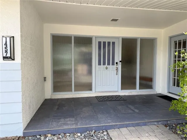 Property entrance featuring stucco siding and large glass panels next to the door(s)