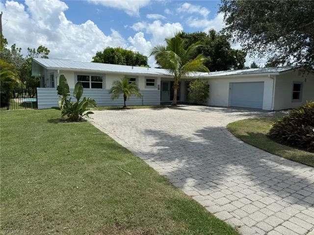 Ranch-style home featuring a metal roof, a garage, and large paver driveway