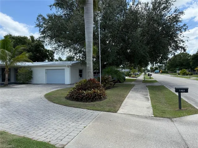Street view of side of property featuring a garage, stucco siding, and decorative driveway