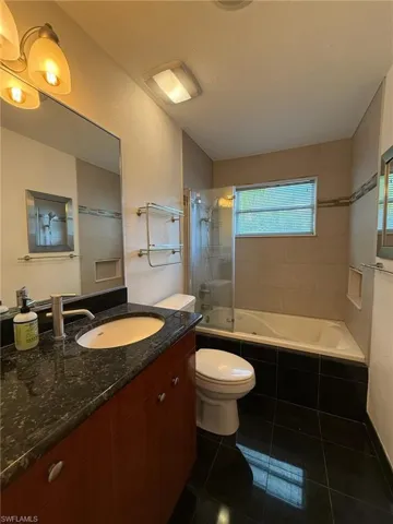 Full bath with vanity, tiled shower / bath, and tile flooring