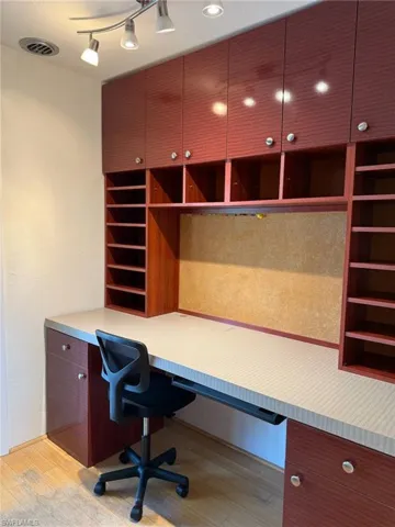 Home office featuring light wood floors and built in desk