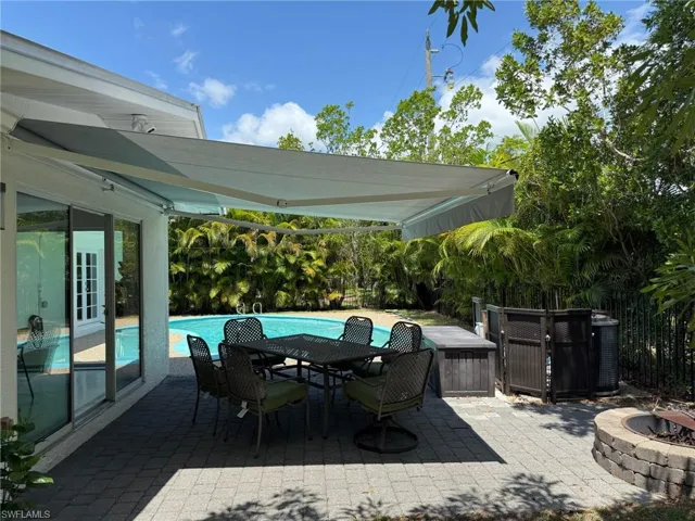 View of patio with an outdoor pool and a fire pit