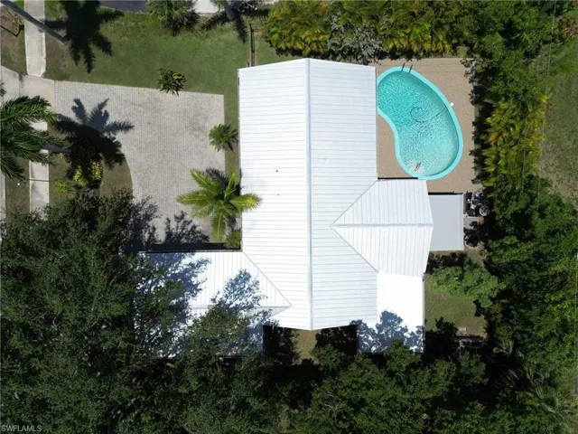 Aerial view of the lot & property with the large paver driveway and pool area