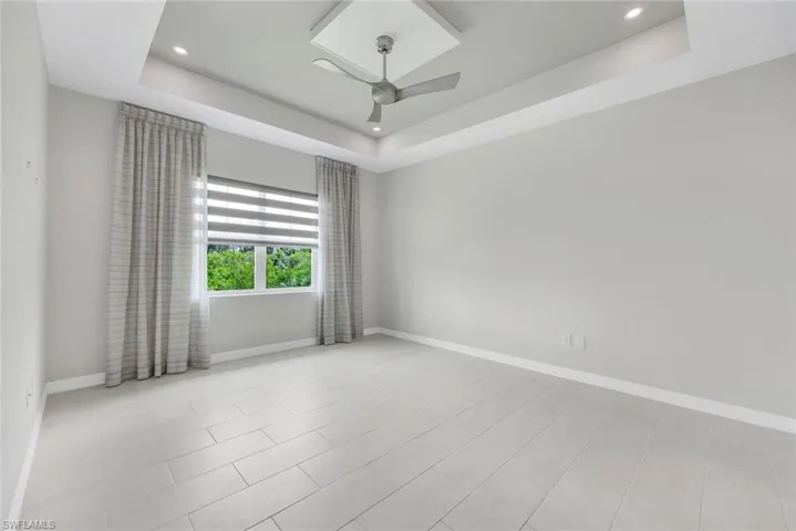 primary bedroom shown empty featuring a tray ceiling and ceiling fan