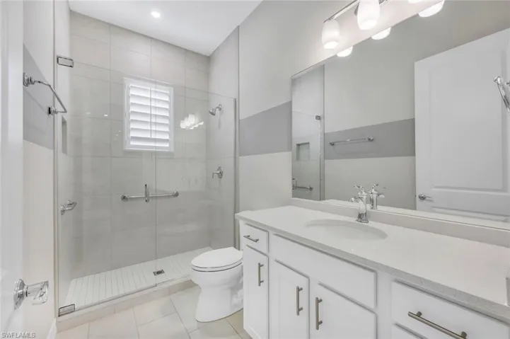 Bathroom with tile patterned floors, a shower with shower door, vanity, and toilet