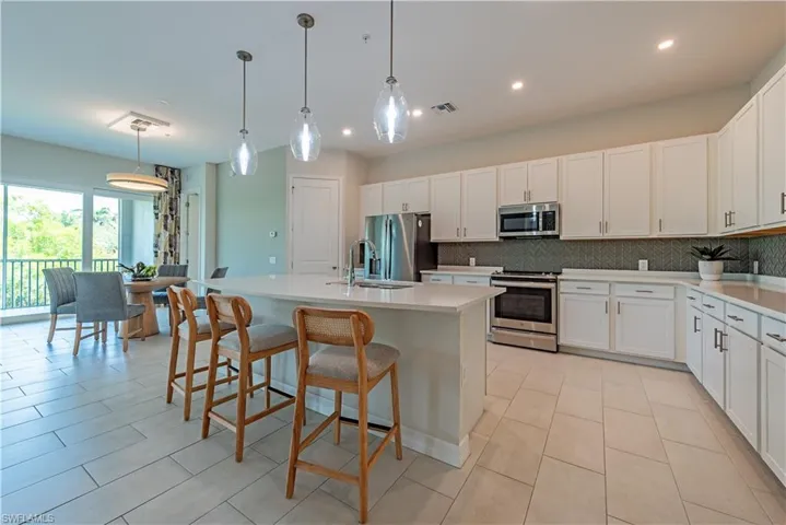Kitchen with stainless steel appliances, light tile patterned flooring, visible vents, backsplash, and light countertops