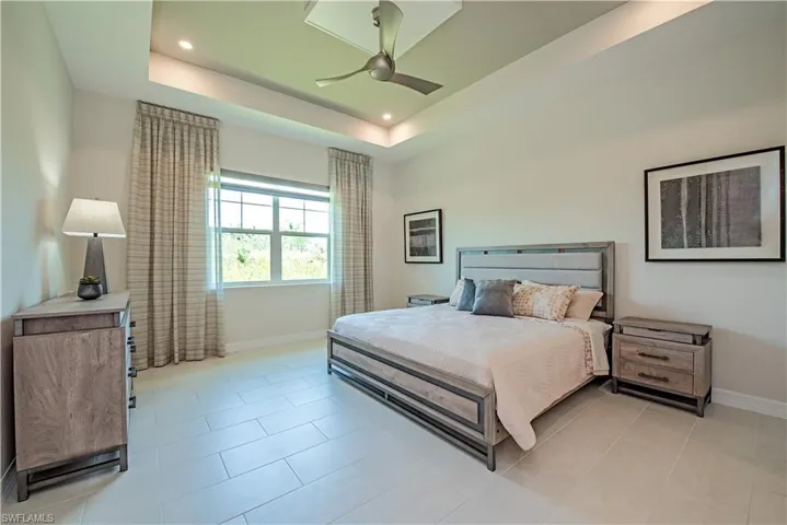 Bedroom with recessed lighting, a raised ceiling, light tile patterned floors, baseboards, and ceiling fan