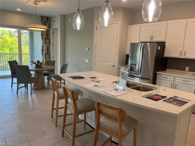 Kitchen with a sink, backsplash, white cabinetry, stainless steel fridge with ice dispenser, and light countertops