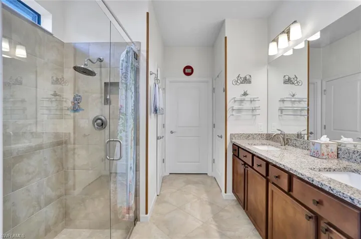 Bathroom with a shower with shower door, dual vanity and tile floors