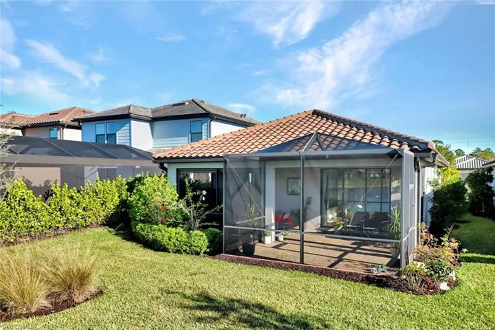 Back of house with a tiled roof, a sunroom and yard