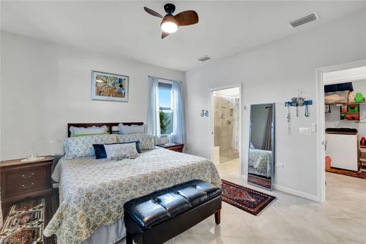 Bedroom with ceiling fan, light tile patterned floors, and ensuite bathroom