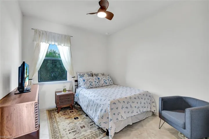 Tiled bedroom with a ceiling fan