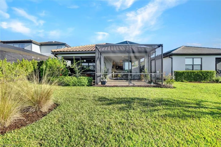 Rear view of property featuring glass enclosure, a sunroom, a tiled roof and a yard