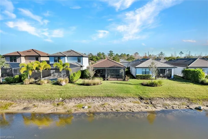 Back of house featuring a sunroom, a yard and a water view