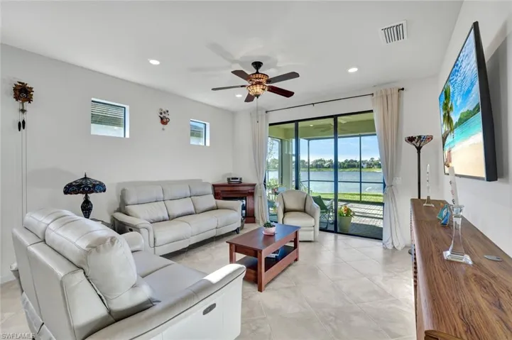 Tiled living room with ceiling fan and a water view