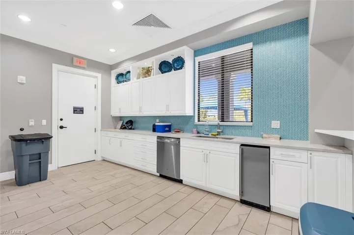 Community Kitchen featuring backsplash, sink, white cabinetry, and stainless steel appliances