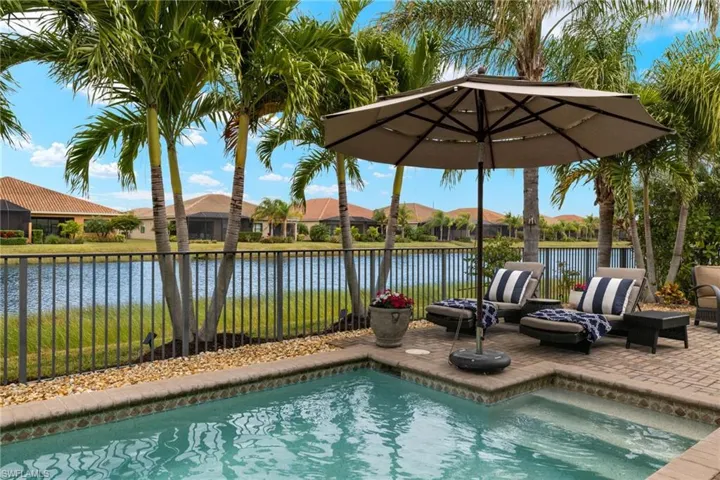 View of swimming pool with a patio and a sunset water view and gorgeous upgraded landscape with palms and landscape lighting