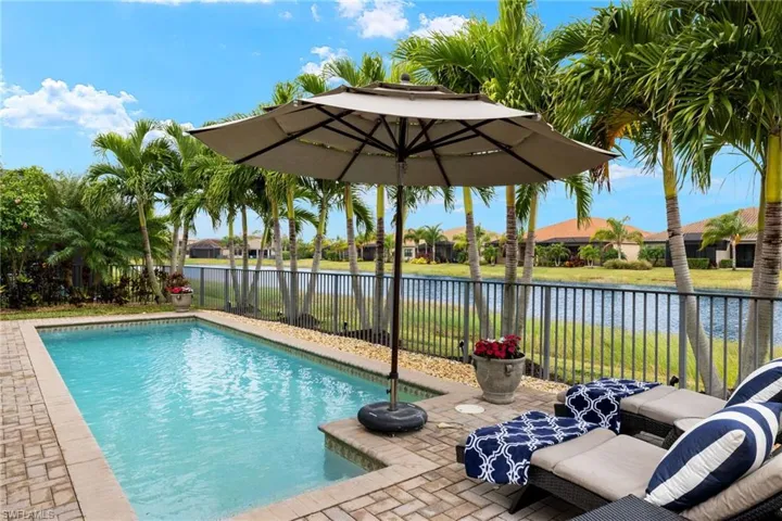View of custom salt water, solar heated swimming pool  featuring a patio and sunset water view and extended lanai for lounging, dining and entertaining. Upgrades include mature Palms and landscape lighting