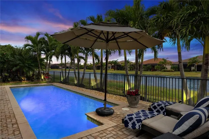 Pool at dusk with a water view and a patio
