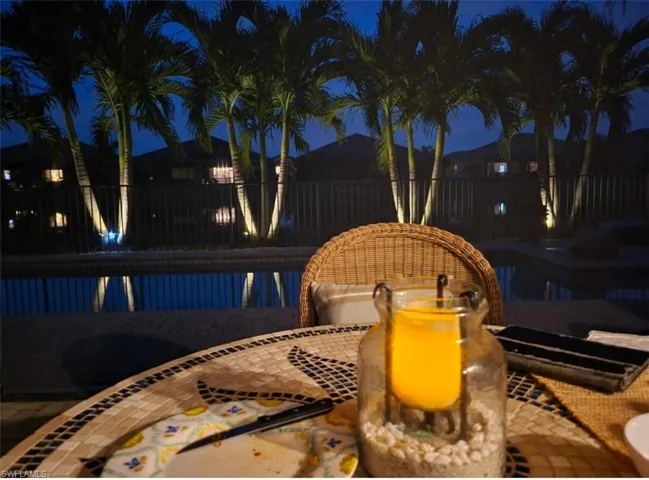 Pool at night featuring a patio and surrounded by palms with professional landscape lighting.