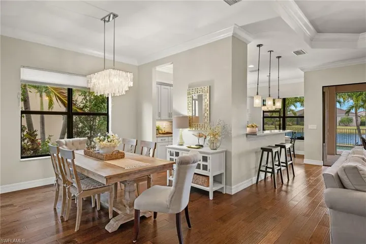 Open and inviting Formal Dining area featuring a decorator chandelier, ornamental molding, and dark wood flooring