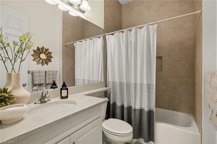 Full guest bathroom featuring vanity and  tiled to ceiling shower / bathtub combination