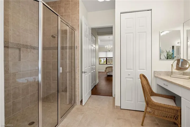 Bathroom with an inviting chandelier, vanity, tile flooring, and full tile to ceiling walk in shower