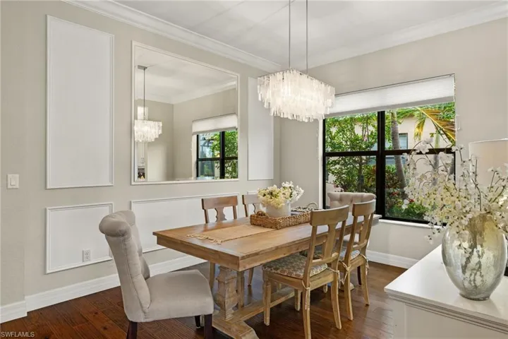 Dining room featuring dark hardwood / wood flooring, ornamental molding and custom wall and mirrors, and a notable coastal chandelier