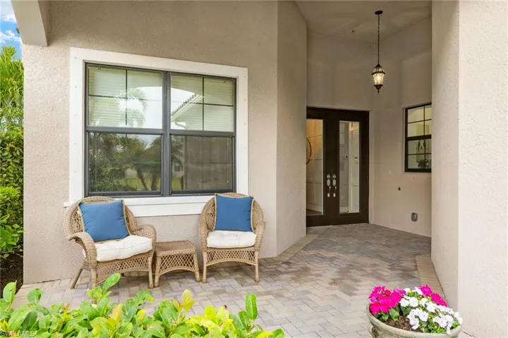 View of exterior entry and front porch with seating for morning coffee