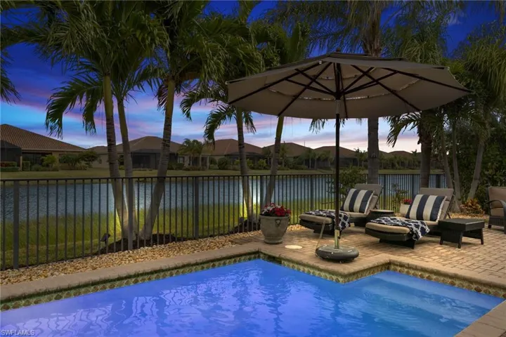 Pool at dusk with a water view and a patio area
