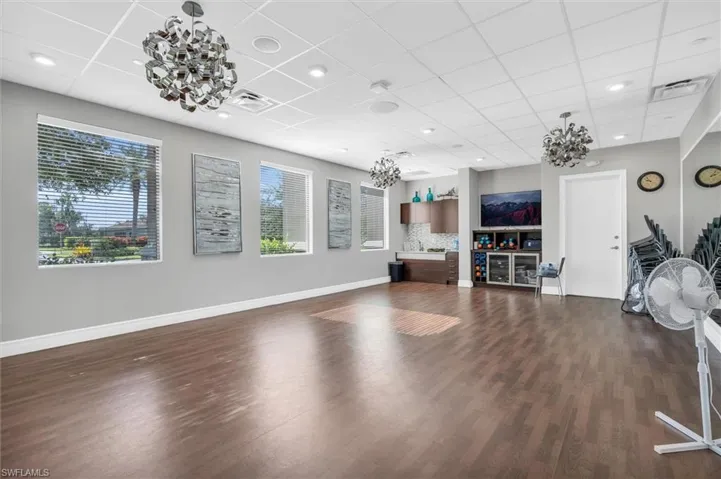 Yoga studio featuring a paneled ceiling, a wealth of natural light, and dark wood-type flooring