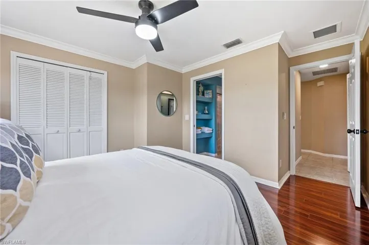 Bedroom featuring dark wood-style floors, ornamental molding, a closet, baseboards, and a ceiling fan