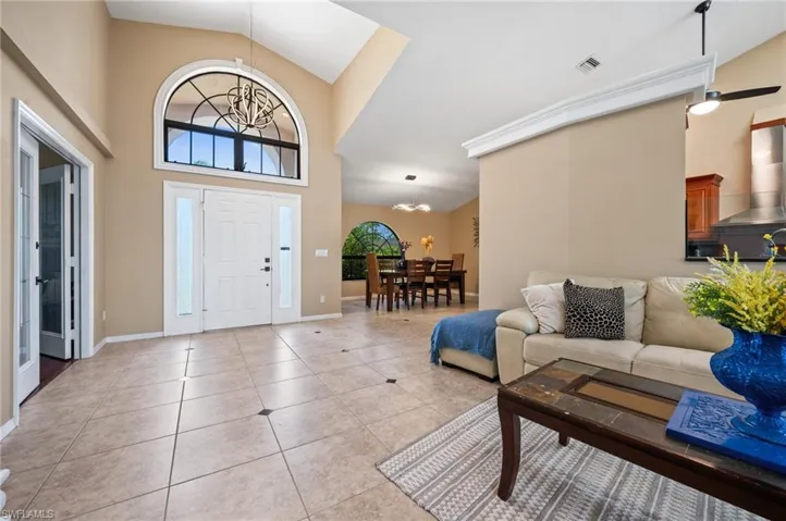 Foyer featuring high vaulted ceiling, light tile patterned floors, baseboards, and a chandelier
