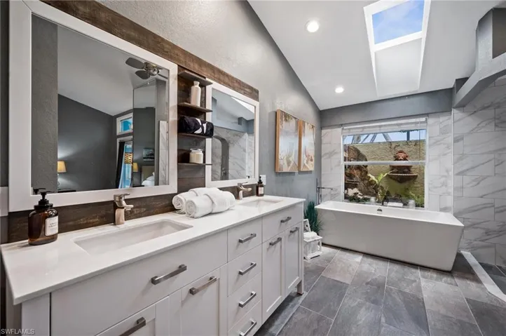 Bathroom with lofted ceiling, double vanity, a freestanding bath, and recessed lighting