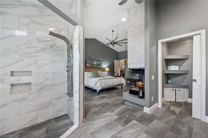 Bedroom with a fireplace, vaulted ceiling, and ceiling fan