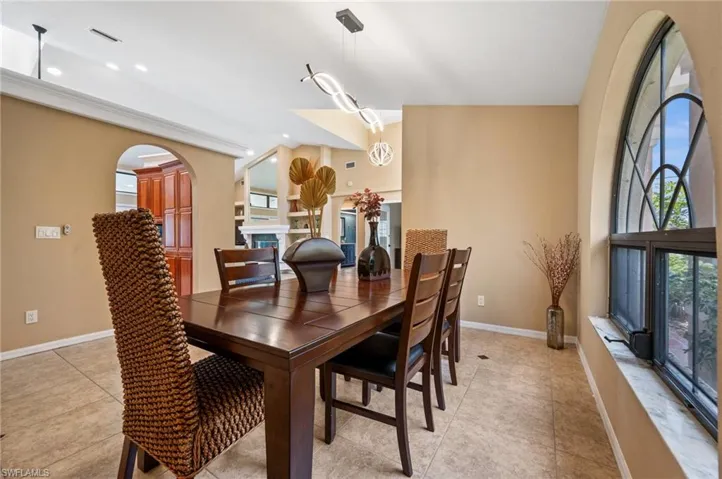 Dining space with baseboards, arched walkways, light tile patterned floors, and recessed lighting